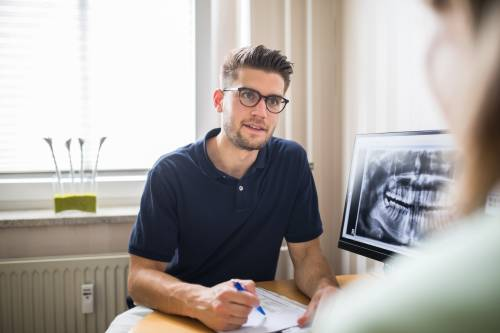 Man sits at desk with dental scans on screen nearby 